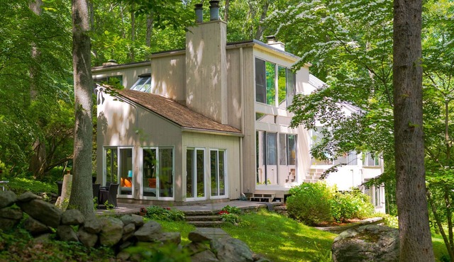 Luxurious midcentury modern glass house in the woods, chefs kitchen & great art
