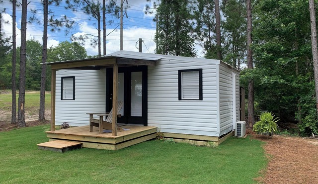 Modern tiny house with large outdoor area and grill.
